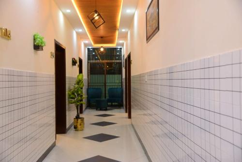 拉合尔Go Guest House Lahore的走廊上设有白色的瓷砖墙壁,地板上设有盆栽植物