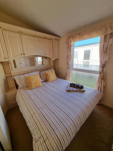 赫彻姆Dog Friendly Caravan Heacham Norfolk Holiday的卧室内的一张床铺,设有大窗户