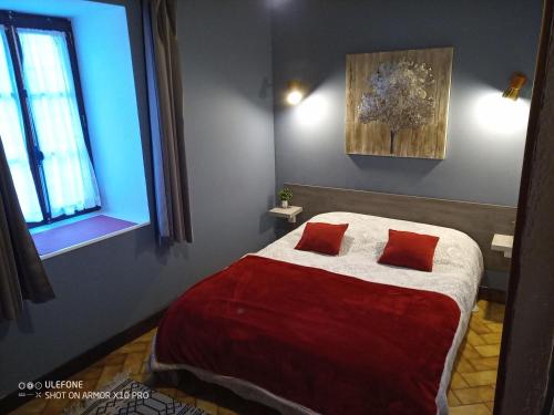 保拉扎克Les gites de Pétrocoriis的一间卧室配有一张大床和两个红色枕头