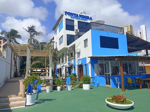 纳塔尔Ponta Negra Suites & Apart的一座蓝白色的建筑,前面有植物