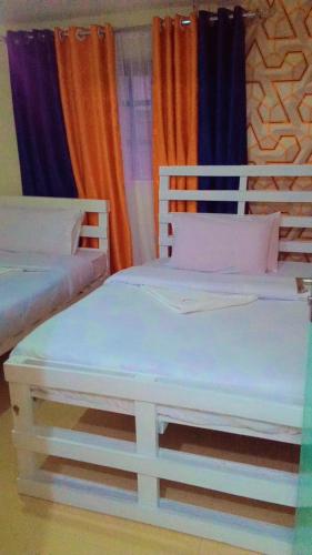 纳库鲁NIKIFLATS的配有窗帘的客房内的2张白色床