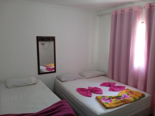 戈亚尼亚Hotel da Creuza的配有两张粉红色窗帘和镜子的客房