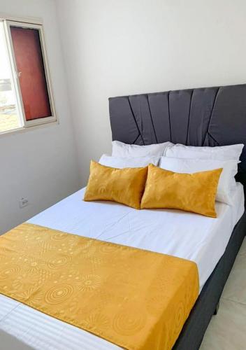 库库塔Acogedor Apartaestudio cerca al aeropuerto的一张带白色床单和黄色枕头的床