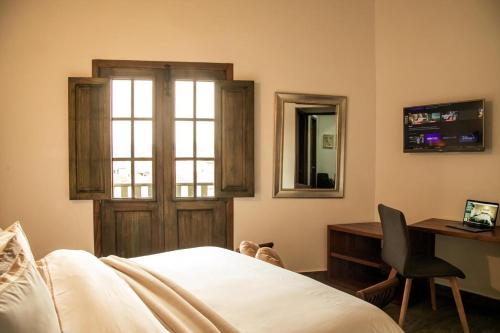 莱瓦镇Santa Lucía Casa Hotel的一间卧室配有一张床、一张书桌和一个窗户。