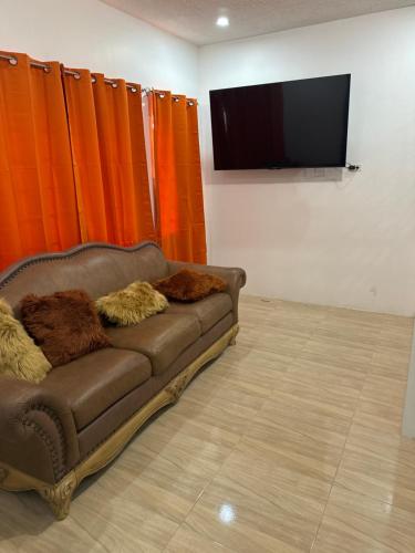 May PenVillas in A Gated Community的棕色沙发,坐在带橙色窗帘的房间