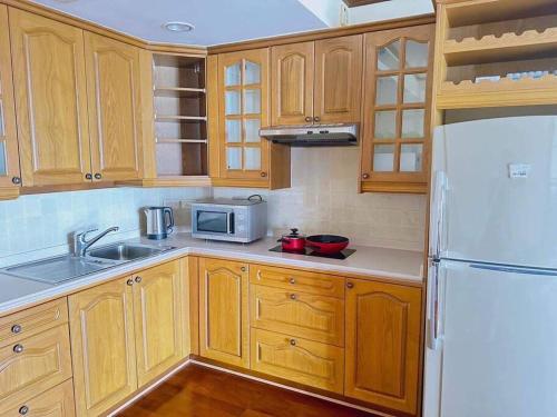 华欣Happy Life Seaview @PalmPavillion的厨房配有木制橱柜和白色冰箱。