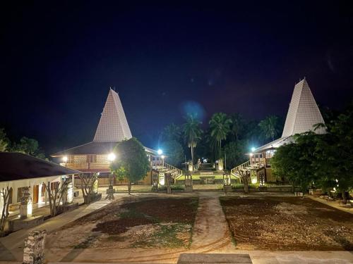LokokakiRumah Budaya Sumba的一群晚上有白色尖顶的建筑
