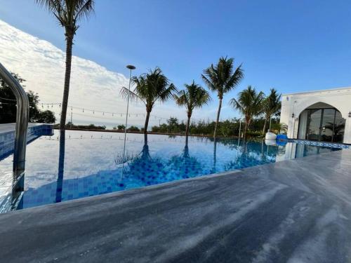 美奈Amanda villa 4 Phan Thiết的一座棕榈树游泳池和一座建筑