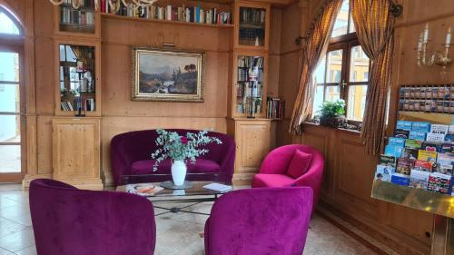 慕尼黑Hotel Lechnerhof Unterföhring的一间设有两把紫色椅子和一张鲜花桌的房间