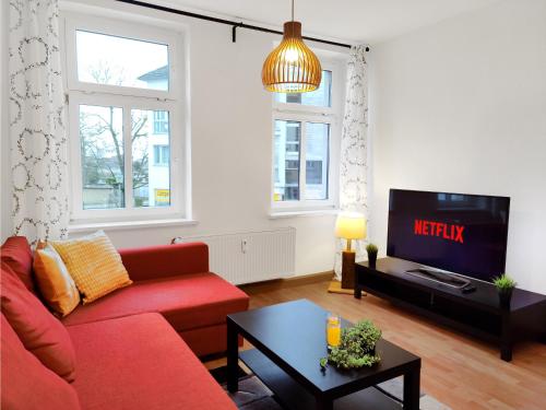 莱比锡Stilvolles Apartment in Leipzig zwischen Flughafen, Messe, Porsche und BMW的客厅配有红色沙发和电视