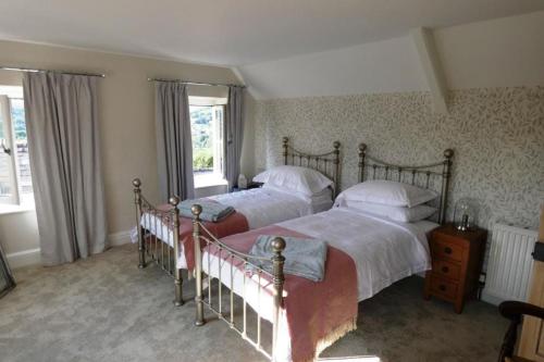 BrimscombeCotswolds cottage near Stroud, with amazing views.的一间卧室设有两张床和两个窗户。