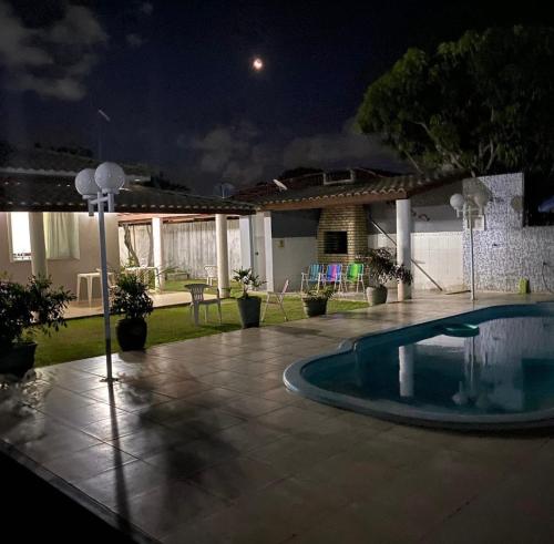 卡马萨里Casa parque do Jacuípe的夜间在院子中间的游泳池