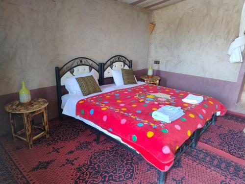 MhamidTaragalte Nomad Camp的一间卧室配有一张带红色毯子的大床