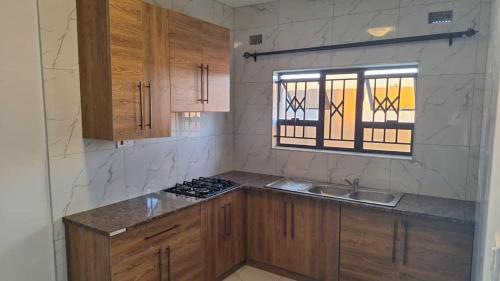 MasvingoLuxury 3 Bedroom Self Catering Apartment- Masvingo的厨房配有木制橱柜、水槽和窗户。