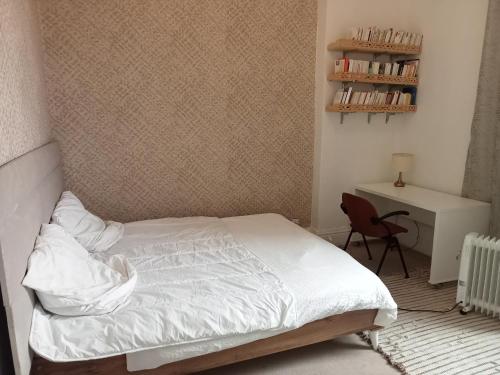 拉马萨Joli appartement de charme的一间卧室配有一张床、一张桌子和一把椅子
