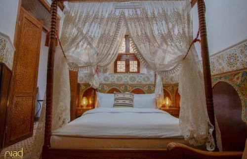 非斯Riad Fes Madaw的卧室配有带白色窗帘的天蓬床