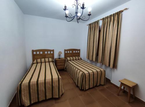 Navas de EstenaCasa Rural María Victoria的一间卧室配有两张床和吊灯。