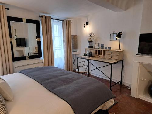 锡斯特龙Hôtel Le Patio de Sophie的一间卧室配有一张床和一张书桌及电视