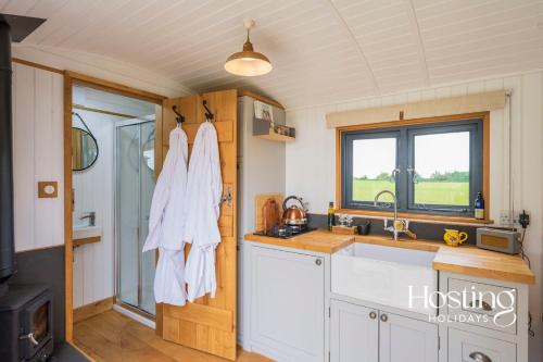 泰姆One Of A Kind Shepherds Hut With Incredible Views的厨房配有白色橱柜、水槽和窗户。