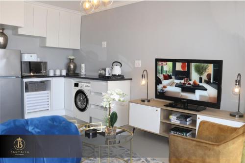马塞卢Barcalla Hotel Apartments的厨房以及带电视和沙发的客厅。