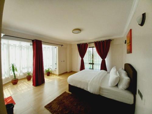 纳库鲁FH apartments opposite culture mambo的一间卧室配有一张带红色窗帘的大床