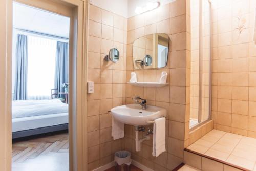波朗特吕Auberge d'Ajoie的一间带水槽和镜子的浴室以及一张床