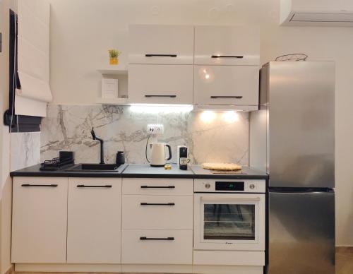 沃洛斯Volos Guesthouse Konstantina的厨房配有白色橱柜和不锈钢冰箱