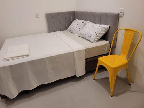 波梅罗迪Hostel & Suítes Stettin的房间里的一张床和一张黄色椅子