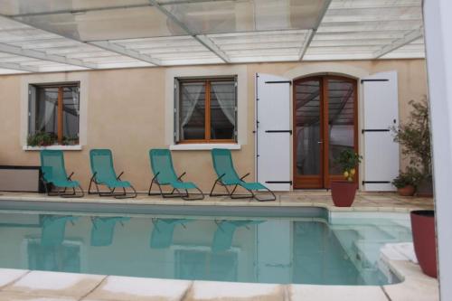 瓦隆蓬达克Gites l’Olivier avec piscine的房屋旁带椅子的游泳池