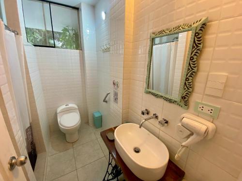 伊察Serenity hotel & lodge的一间带卫生间、水槽和镜子的浴室