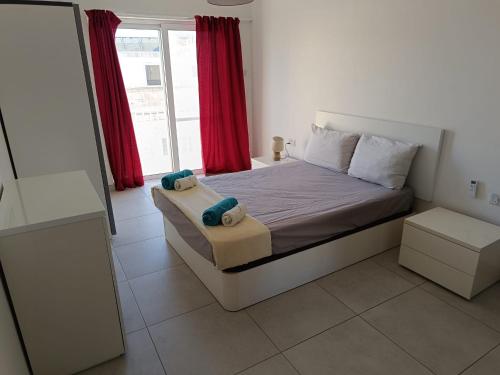 纳杜尔Gozo Spacious 3 Bathroom Apartment的一间卧室配有床和红色窗帘的窗户