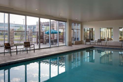 欧文DFW凯悦嘉轩酒店的房屋内带椅子和桌子的游泳池