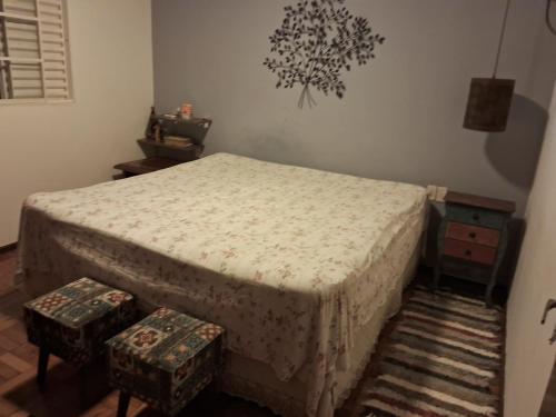 阿拉沙Aconchego的一间卧室配有一张床和两张凳子