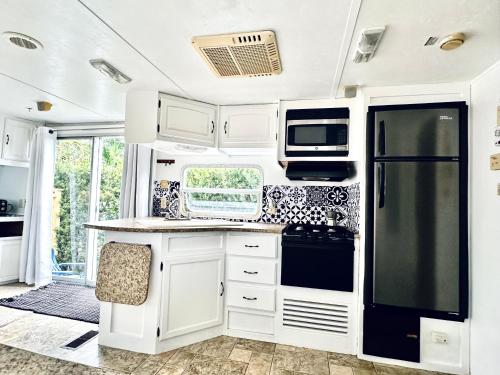 迈阿密Descanso, tranquilidad y desconexión a un paso de todo.的厨房配有白色橱柜和黑色冰箱。