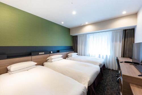 东京Hotel Kazusaya的酒店客房设有三张床和一张书桌