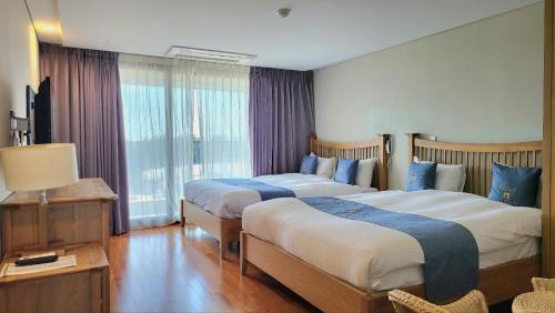 西归浦市IlleInn Hotel的酒店客房设有两张床和窗户。