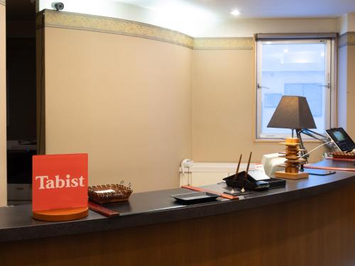 弘前市Tabist Hirosaki Touei Hotel的办公室,桌子上有一个标牌