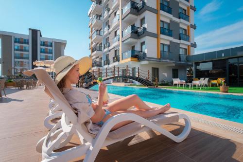 安塔利亚Elysium Deluxe Suites Antalya的坐在游泳池旁椅子上的女人