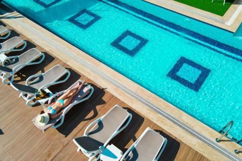 安塔利亚Elysium Deluxe Suites Antalya的游泳池的顶部景色,设有一排椅子