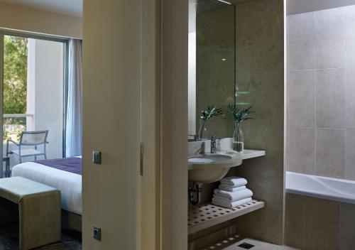 阿默达拉-伊拉克利翁Atlantica Akti Zeus Hotel的一间带水槽和镜子的浴室以及一张床