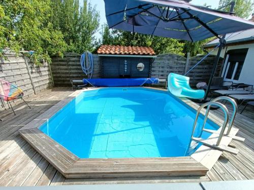 圣让-德蒙Apb-Spa cottages et Apb BnB avec piscine的木制甲板上带遮阳伞的游泳池