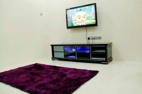 Bukit Kayu HitamHomestay Maya Bukit Kayu Hitam的一间带电视和紫色地毯的客厅