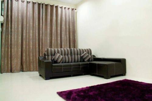 Bukit Kayu HitamHomestay Maya Bukit Kayu Hitam的客厅里一张棕色的沙发,铺着紫色地毯