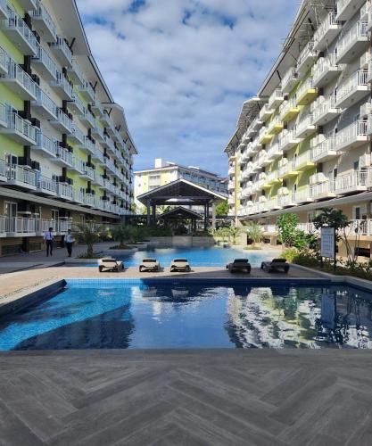 PusokCondo Azur Suites A326 Amani Resorts Residences , 5 minutes Airport, Netflix, Stylish, Cozy with Luxurious Swimming Pool的两个公寓大楼中间的一个游泳池