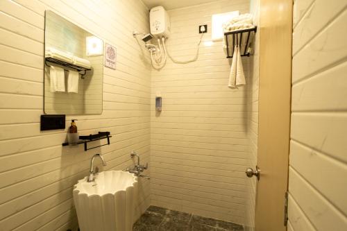 MundraClick Hotel Mundra的白色的浴室设有水槽和淋浴。