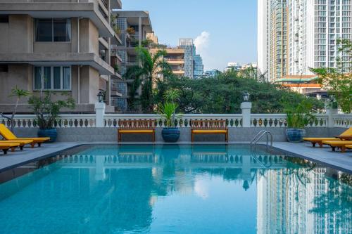 曼谷曼谷素坤逸大道酒店的一个带长椅和建筑物的游泳池
