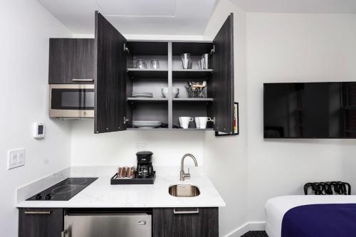 波士顿Stylish Studio in Historic Boston - Unit #404的厨房配有黑色橱柜、水槽和床。