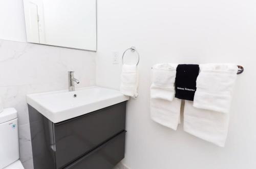 波士顿Modern Suite in Fenway Neighborhood的白色的浴室设有水槽和毛巾。