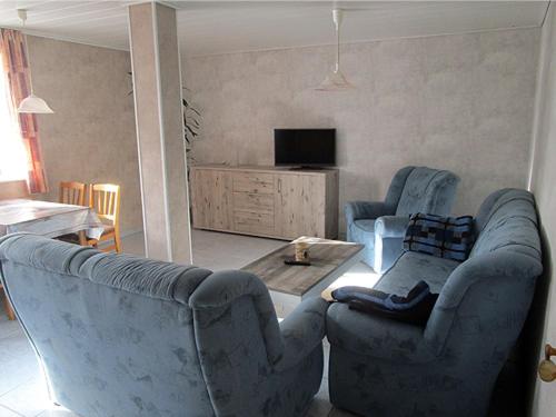 朗格内斯岛Ferienwohnung Uthlande的客厅配有2把蓝色椅子和桌子