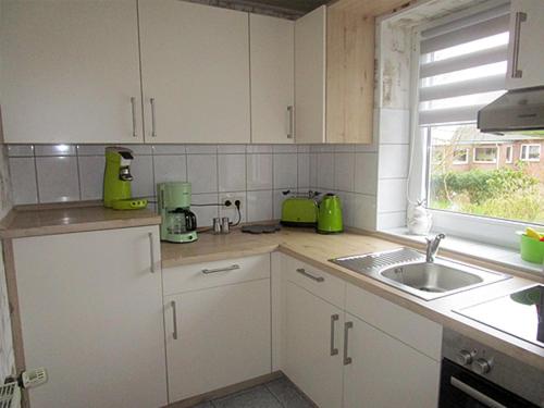 朗格内斯岛Ferienwohnung Uthlande的厨房配有白色橱柜、水槽和窗户。